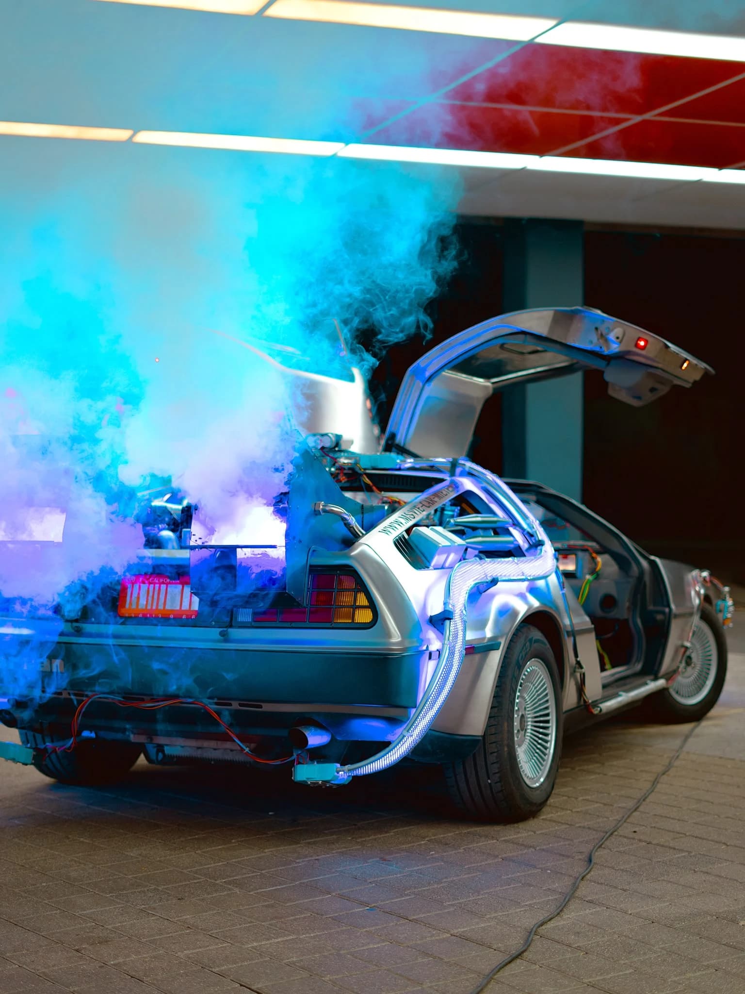 Silberner Wagen mit geöffneten Flügeltüren und farbigem Rauch